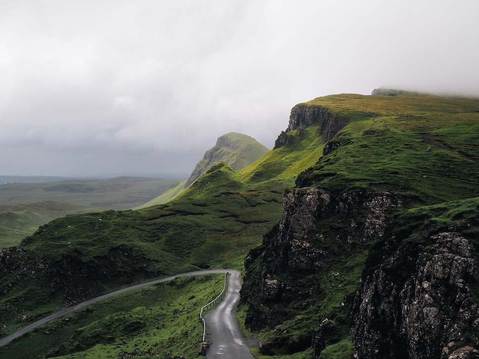 Picturesque country road with lush greenery juxtaposed with a gloomy sky.